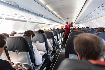 Image showing Interior of commercial airplane with passengers on their seats during flight.