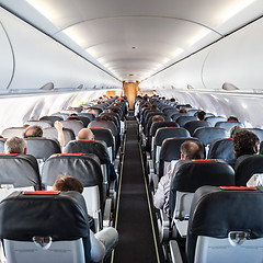 Image showing Interior of commercial airplane with passengers on their seats during flight.