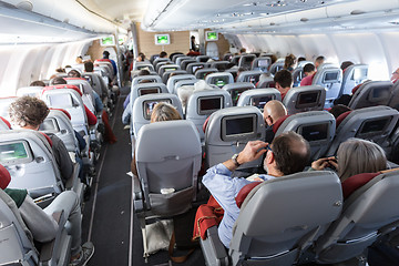 Image showing Interior of large commercial airplane with passengers on their seats during flight.