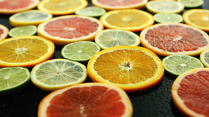 Image showing Slices of citruses on dark table 