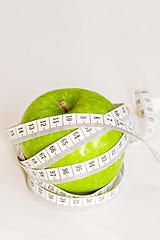 Image showing Measuring tape wrapped around a green apple.