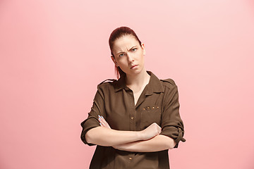 Image showing The serious business woman standing and looking at camera against pink background.