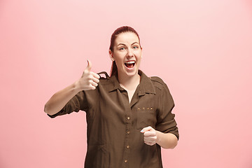 Image showing The happy business woman standing and smiling against pink background.