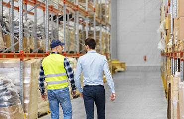 Image showing worker and businessman walking along warehouse