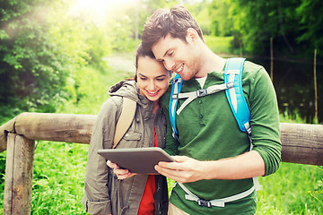 Image showing happy couple with backpacks and tablet pc outdoors