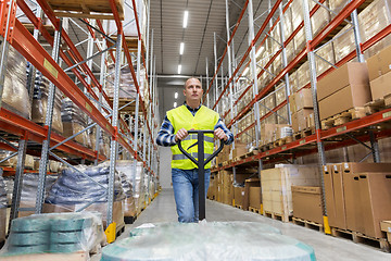 Image showing warehouse worker carrying loader with goods