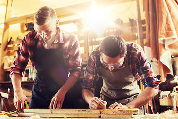 Image showing carpenters with ruler and wood plank at workshop