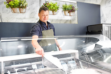 Image showing male seller adding ice to fridge at grocery store