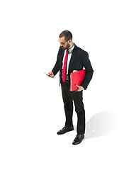 Image showing Serious businessman wiht mobile phone with folder in hand isolated over white background in studio