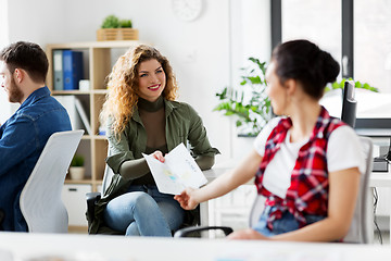 Image showing female office workers giving each other papers