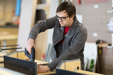 Image showing assembler with screwdriver making furniture