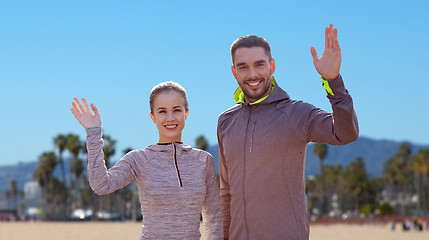Image showing smiling couple in sport clothes waving hand