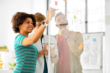 Image showing creative team writing on glass board at office