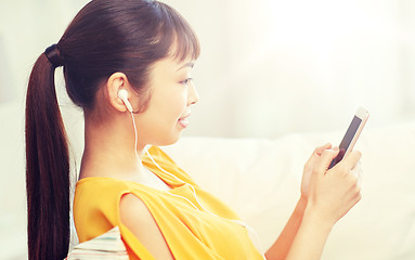Image showing happy asian woman with smartphone and earphones