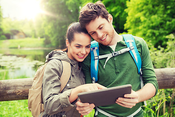 Image showing happy couple with backpacks and tablet pc outdoors