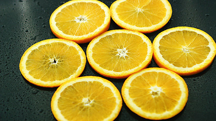 Image showing Orange slices on dark desk 
