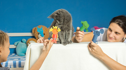 Image showing Mom and daughter play a puppet theater with a tired cat