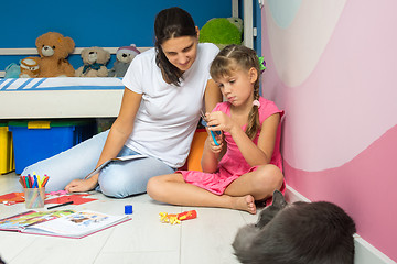 Image showing My daughter and mother are making figures from colored paper, a cat is sleeping nearby