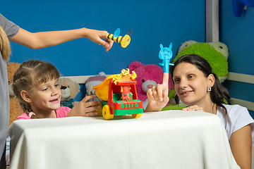Image showing An enthusiastic mother plays with daughters in a self-made finger puppet theater