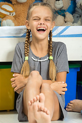 Image showing The girl cheerfully laughs sitting by the bed