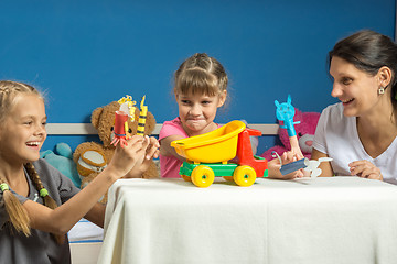 Image showing Mom plays with two daughters in a self-made finger puppet theater