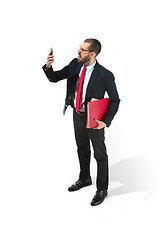 Image showing Angry businessman talking on the phone with folder in hand isolated over white background in studio shooting