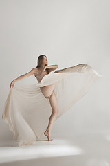 Image showing Young beautiful dancer in beige swimsuit dancing on gray background