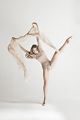 Image showing Young beautiful dancer in beige swimsuit dancing on gray background