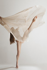 Image showing Young beautiful dancer in beige swimsuit dancing on gray background