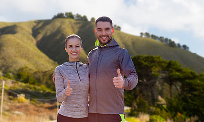 Image showing smiling couple in sport clothes showing thumbs up