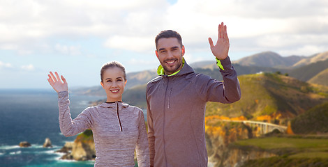 Image showing smiling couple in sport clothes waving hand