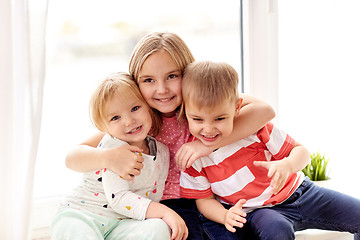 Image showing happy little kids hugging at window