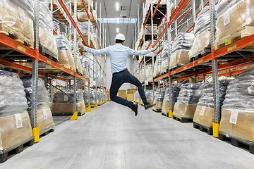 Image showing happy businessman in helmet jumping at warehouse