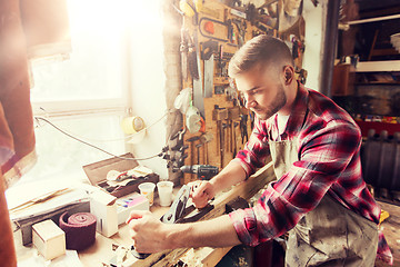 Image showing carpenter working with plane and wood at workshop