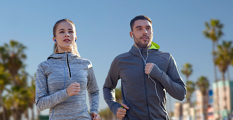 Image showing couple with earphones running over venice beach