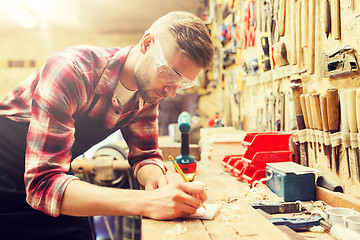 Image showing carpenter writing to notebook at workshop