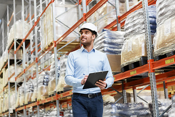 Image showing businessman in helmet with clipboard at warehouse