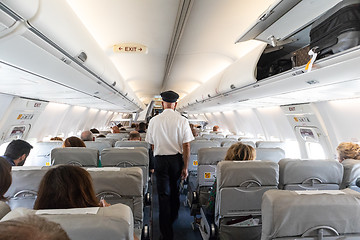 Image showing Interior of commercial airplane with passengers on their seats during flight.