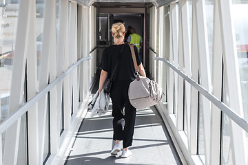 Image showing Female passenger carrying the hand luggage bag, walking the airplane boarding corridor.