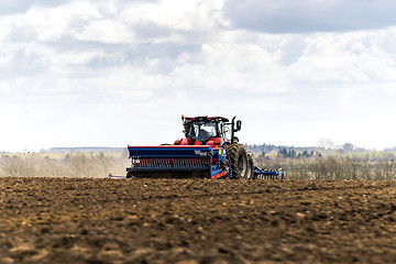 Image showing Red tractor driving on a field