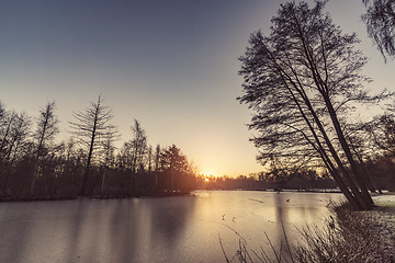 Image showing Frozen lake with tree silhouttes on the shore