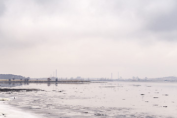 Image showing Frozen lake by a city with industrial buildings