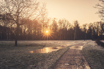 Image showing Sunrise in the winter reflecting in a frozen puddle