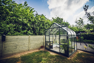 Image showing Greenhouse in a garden with trees behind