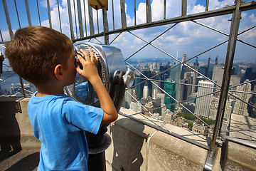 Image showing Little boy using binoculars and watched on the New York Skyline 