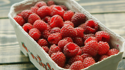 Image showing Container with ripe raspberry on wooden desk 