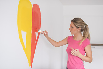 Image showing woman painting a heart on the wall