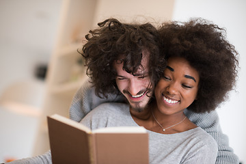 Image showing multiethnic couple hugging in front of fireplace