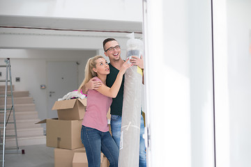 Image showing couple carrying a carpet moving in to new home