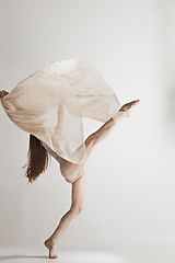 Image showing Young beautiful dancer in beige swimsuit dancing on gray background